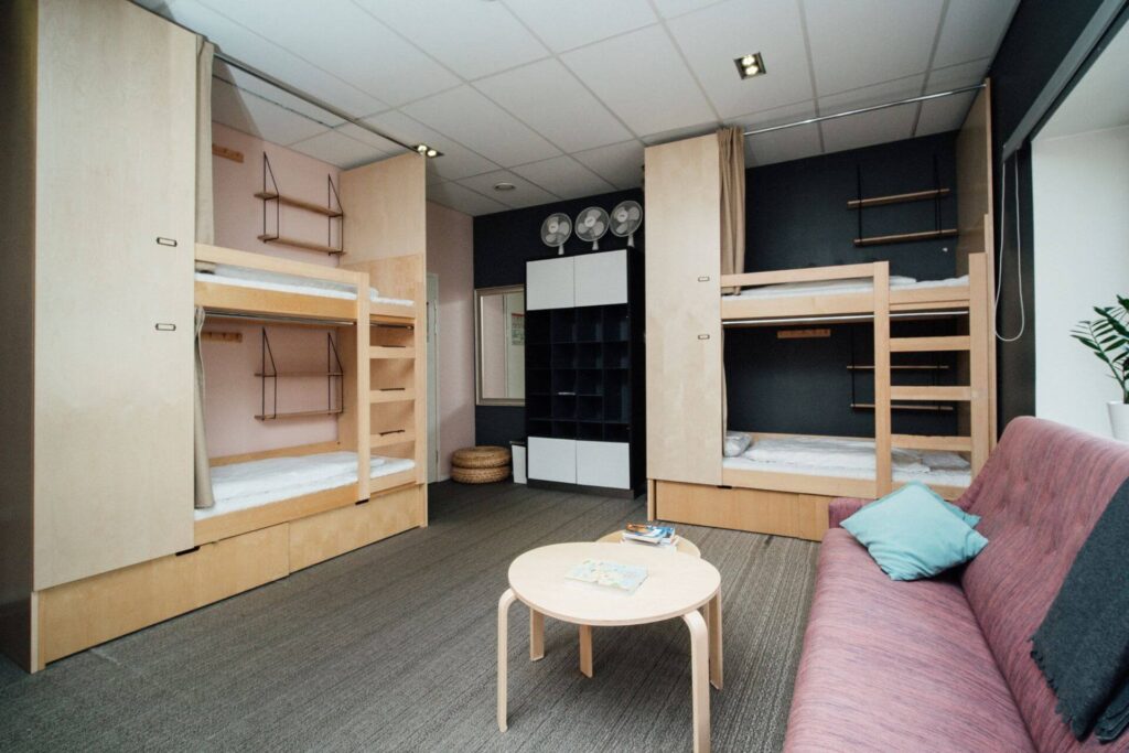 the 6-bed female dorm at the yard hostel Helsinki. Only 2 bunk beds are shown with a pink sofa and a table.